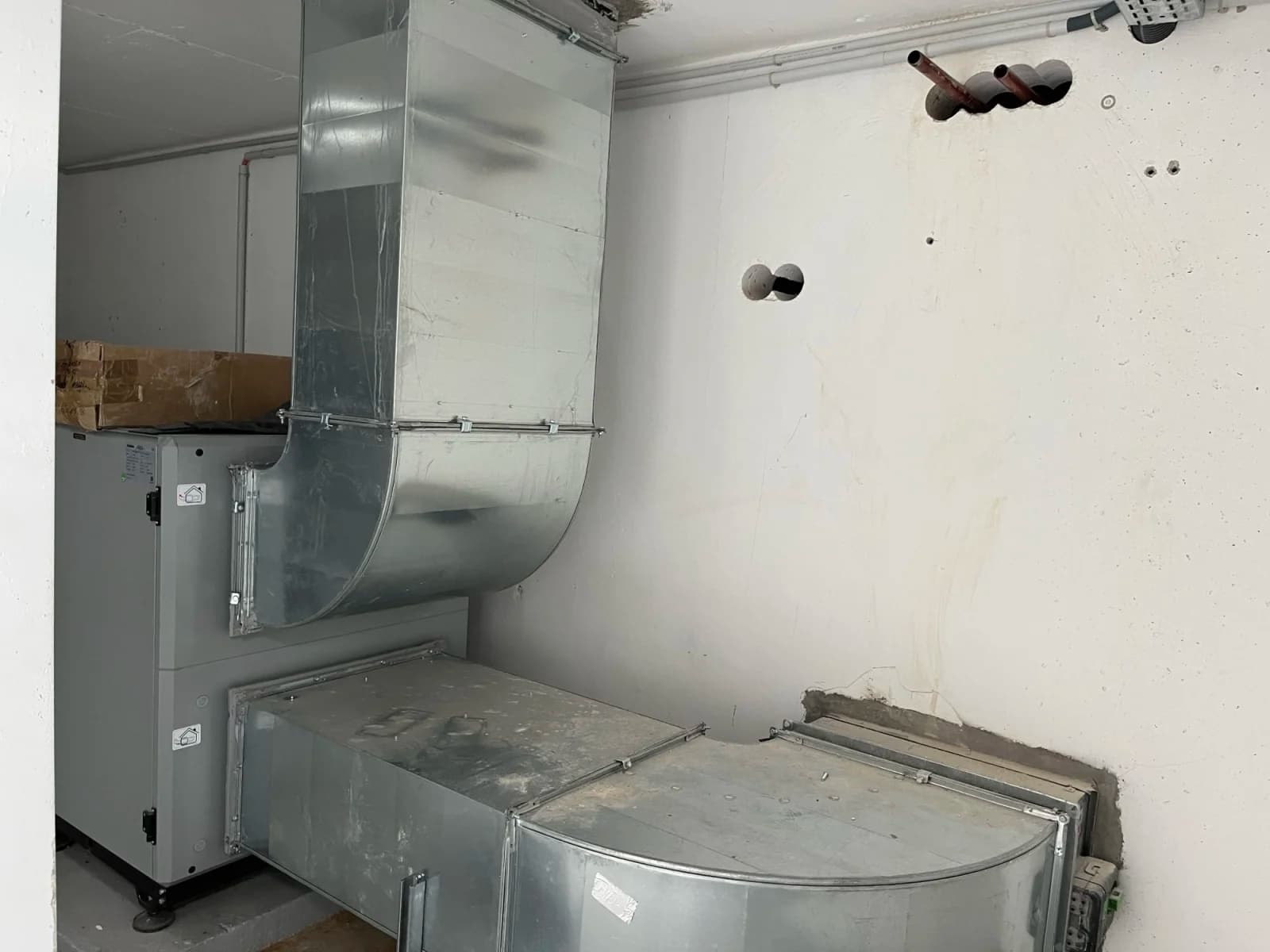 Réseau de gaines métalliques raccordé à une unité de ventilation dans un local technique